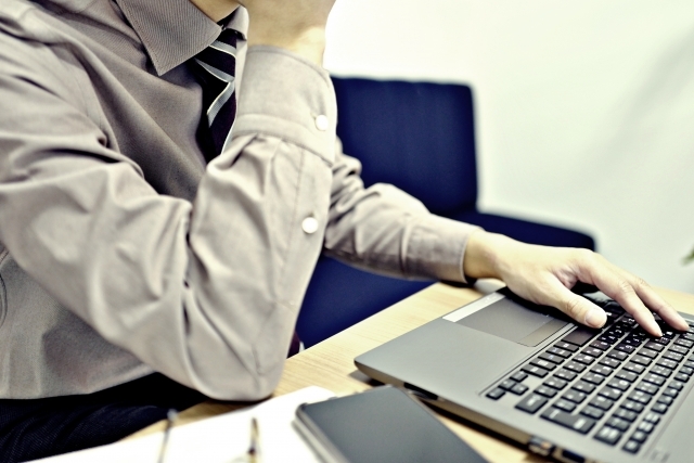 パソコンを見るスーツの男性の画像